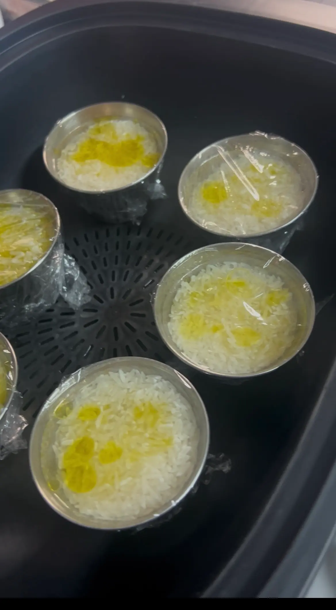 Step 2. Preparar 6 moldes con 50g de arroz, 85g de agua, una cucharadita de aceite y una pizca de sal, cubrir con filtrasnparente cada uno y reservar en varoma. illustration