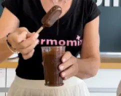 Step <p>Ponemos ese chocolate en un vaso, y vamos sumergiendo los helados en el chocolate hasta que estén completamente bañados. Escurrimos y lo ponemos que un plato con forrado con papel de hornear, de ese forma podremos meterlo en el congelador hasta su consumo.</p> illustration