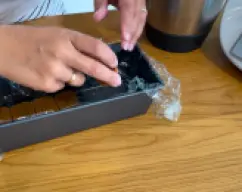 Step <p>Forramos con papel fim un molde alargado, y ponemos en el fondo una tanda de galletas Lotus. A continuación rellenamos el molde con la mezcla que hemos preparado.</p> illustration